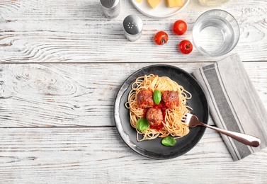Photo of Delicious pasta with meatballs and tomato sauce on wooden background, flat lay