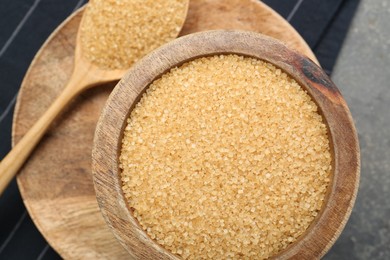 Brown sugar in bowl and spoon on grey table, top view