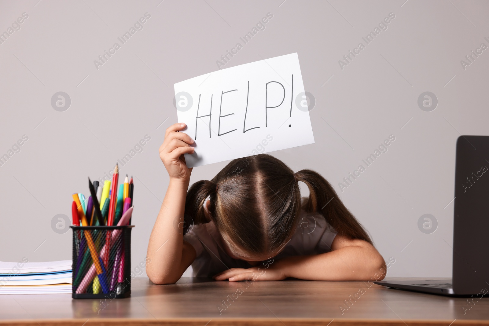 Photo of Dyslexia concept. Little girl holding paper with word Help at wooden table