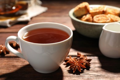 Photo of Cup of aromatic hot tea with anise stars on wooden table