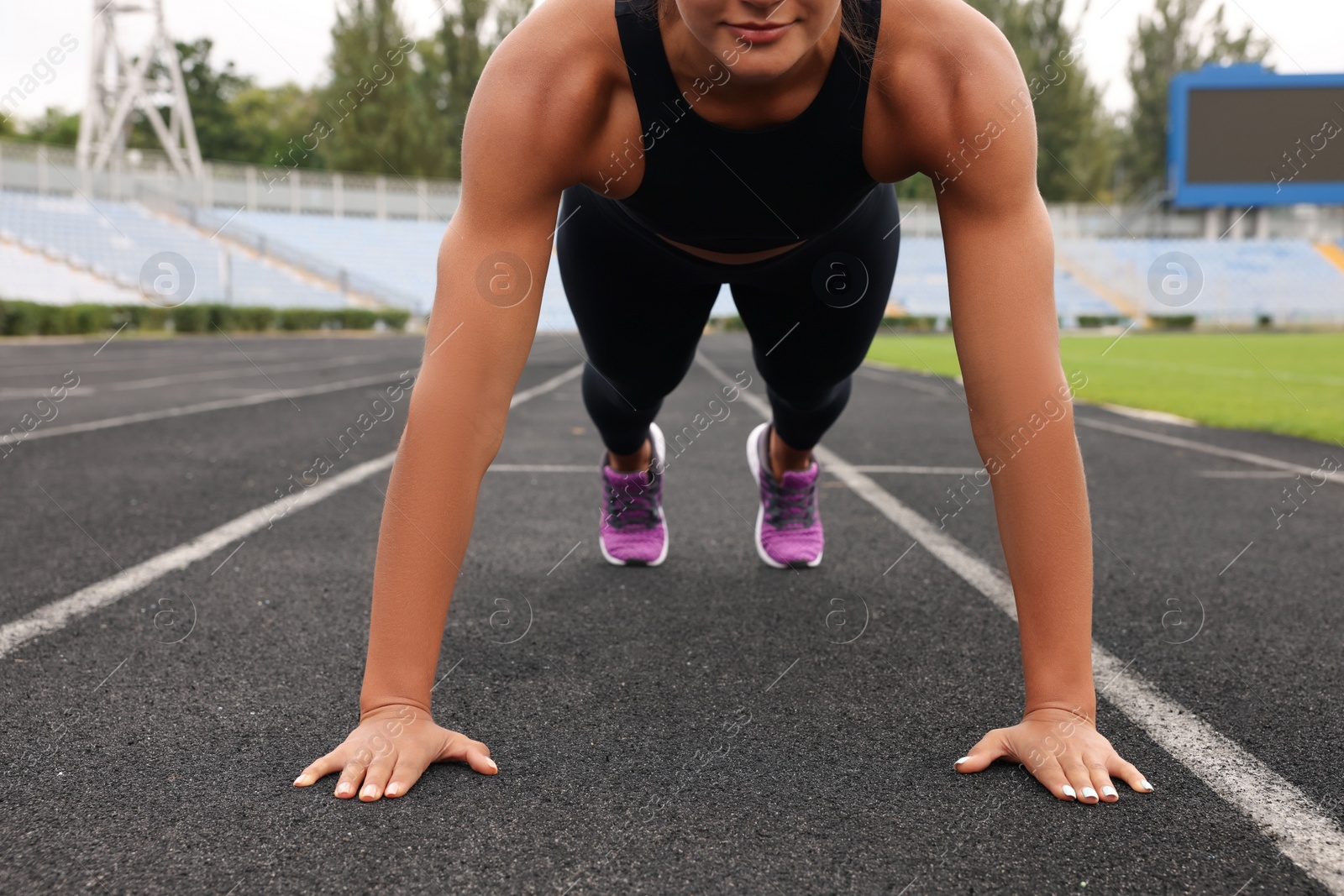 Photo of Young woman doing high plank exercise at stadium, closeup