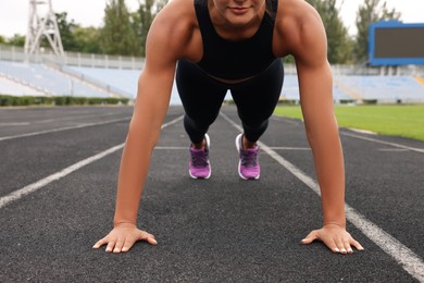 Photo of Young woman doing high plank exercise at stadium, closeup