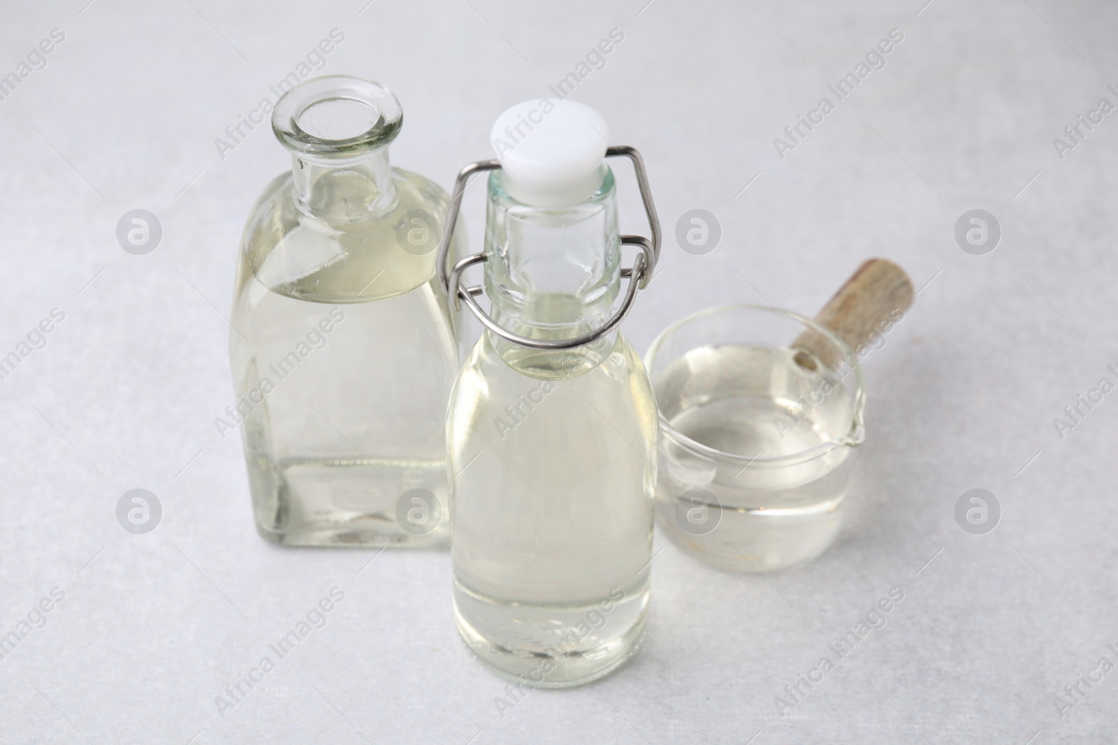 Photo of Vinegar in glass bottles and saucepan on light table