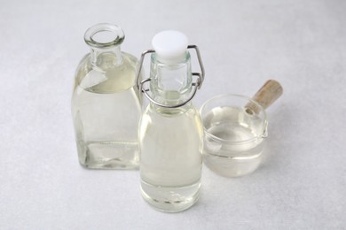 Vinegar in glass bottles and saucepan on light table