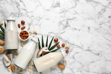 Vegan milk and different nuts on white marble table, flat lay. Space for text
