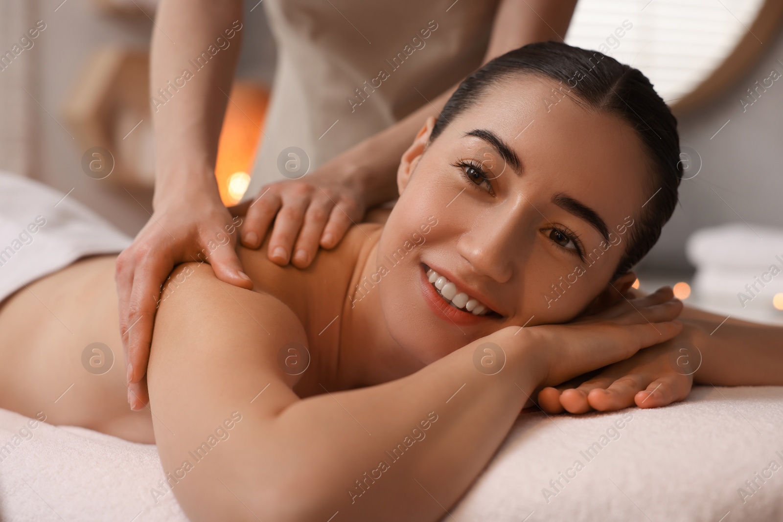 Photo of Woman receiving back massage on couch in spa salon