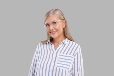 Portrait of beautiful middle aged woman in eyeglasses on light grey background