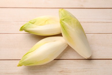 Raw ripe chicories on wooden table, top view