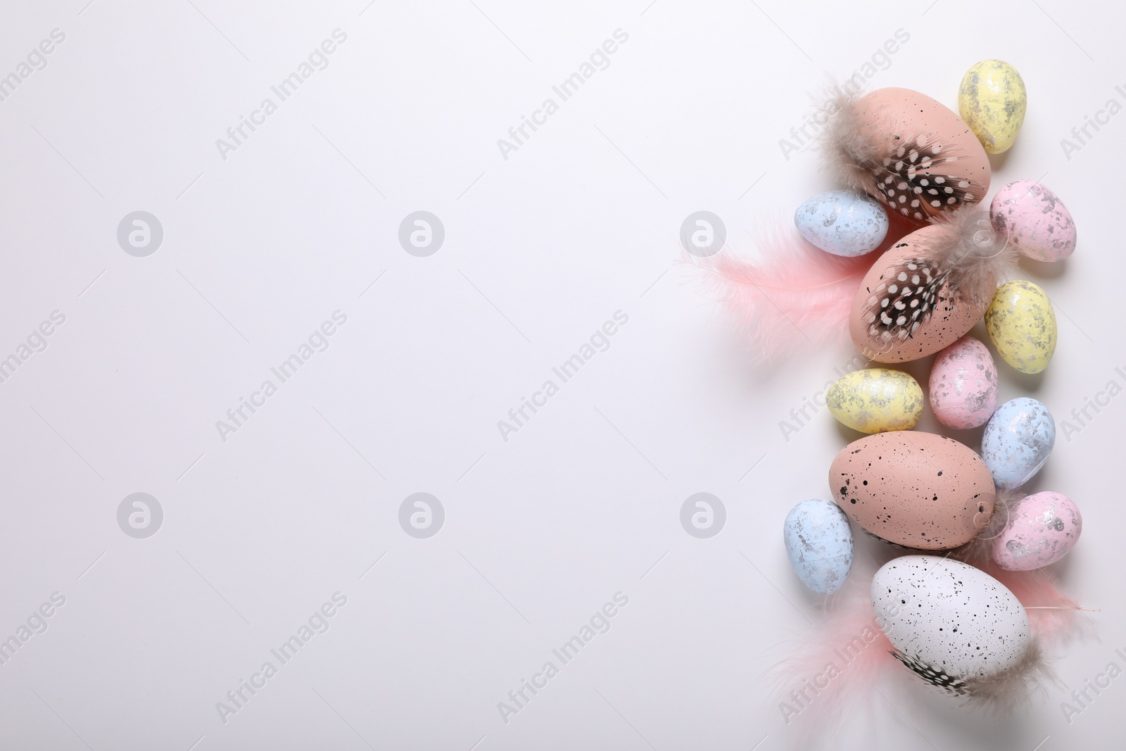 Photo of Many painted Easter eggs with feathers on white background, flat lay. Space for text