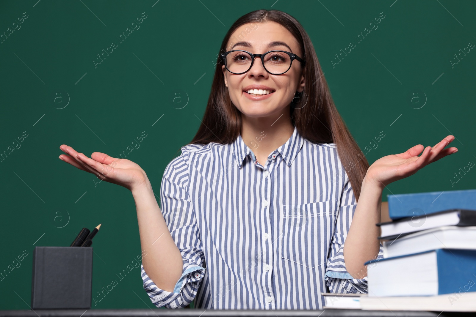 Photo of Portrait of young teacher at table against green background