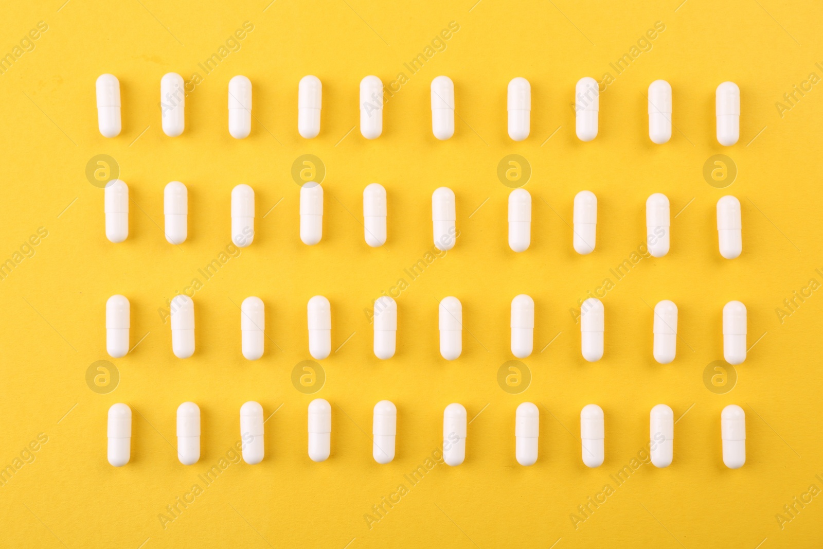 Photo of Many vitamin capsules on orange background, flat lay