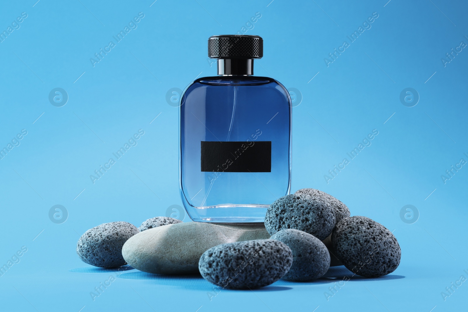 Photo of Stylish presentation of luxury men`s perfume on stones against light blue background