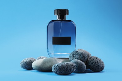 Stylish presentation of luxury men`s perfume on stones against light blue background