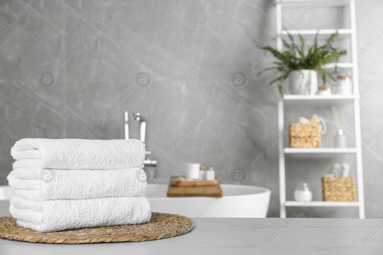 Photo of Stacked bath towels on light table in bathroom. Space for text