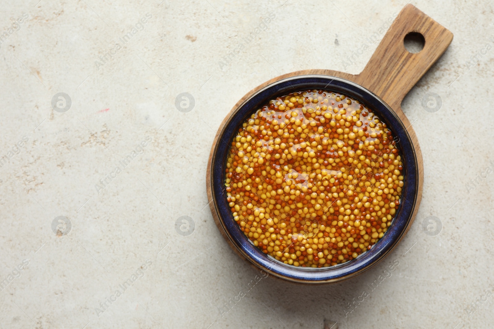 Photo of Whole grain mustard in bowl on light table, top view. Space for text