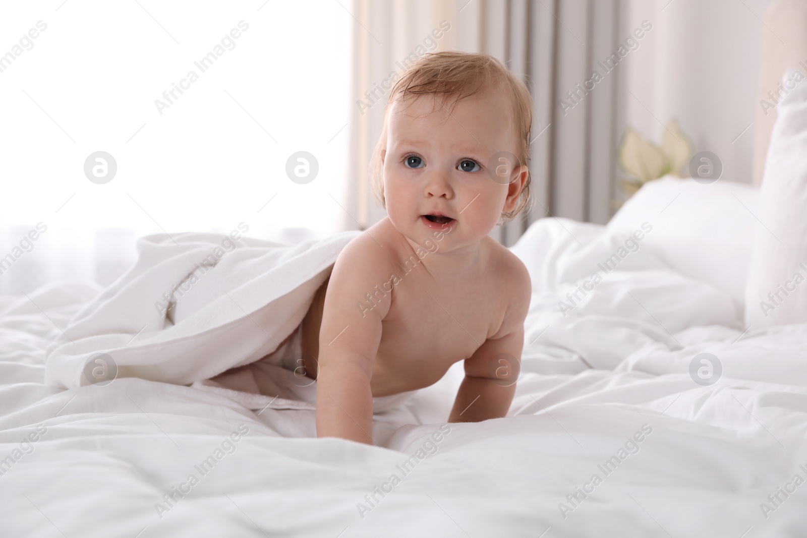 Photo of Cute little baby with soft towel on bed after bath