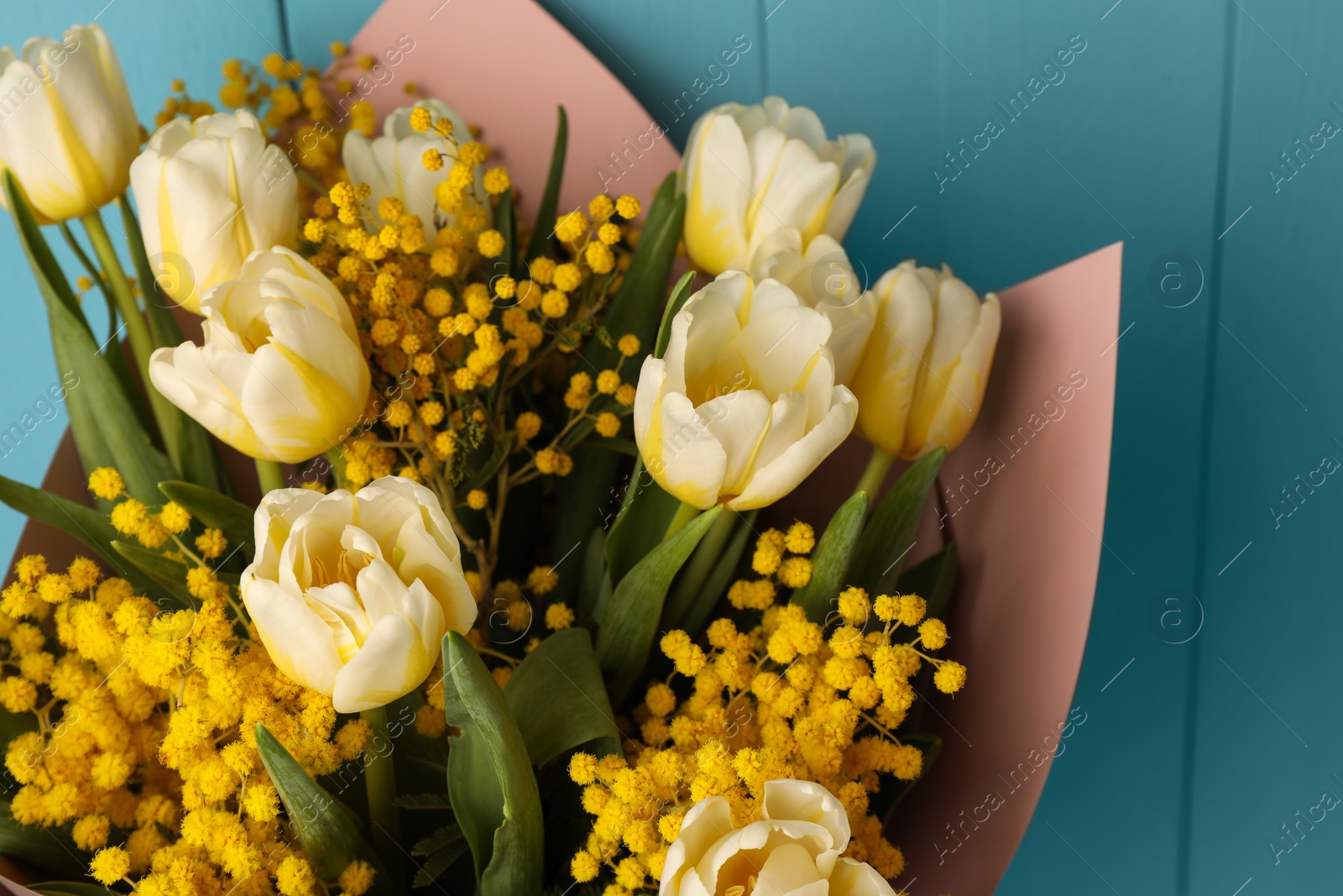 Photo of Bouquet of beautiful spring flowers near turquoise wooden wall, closeup