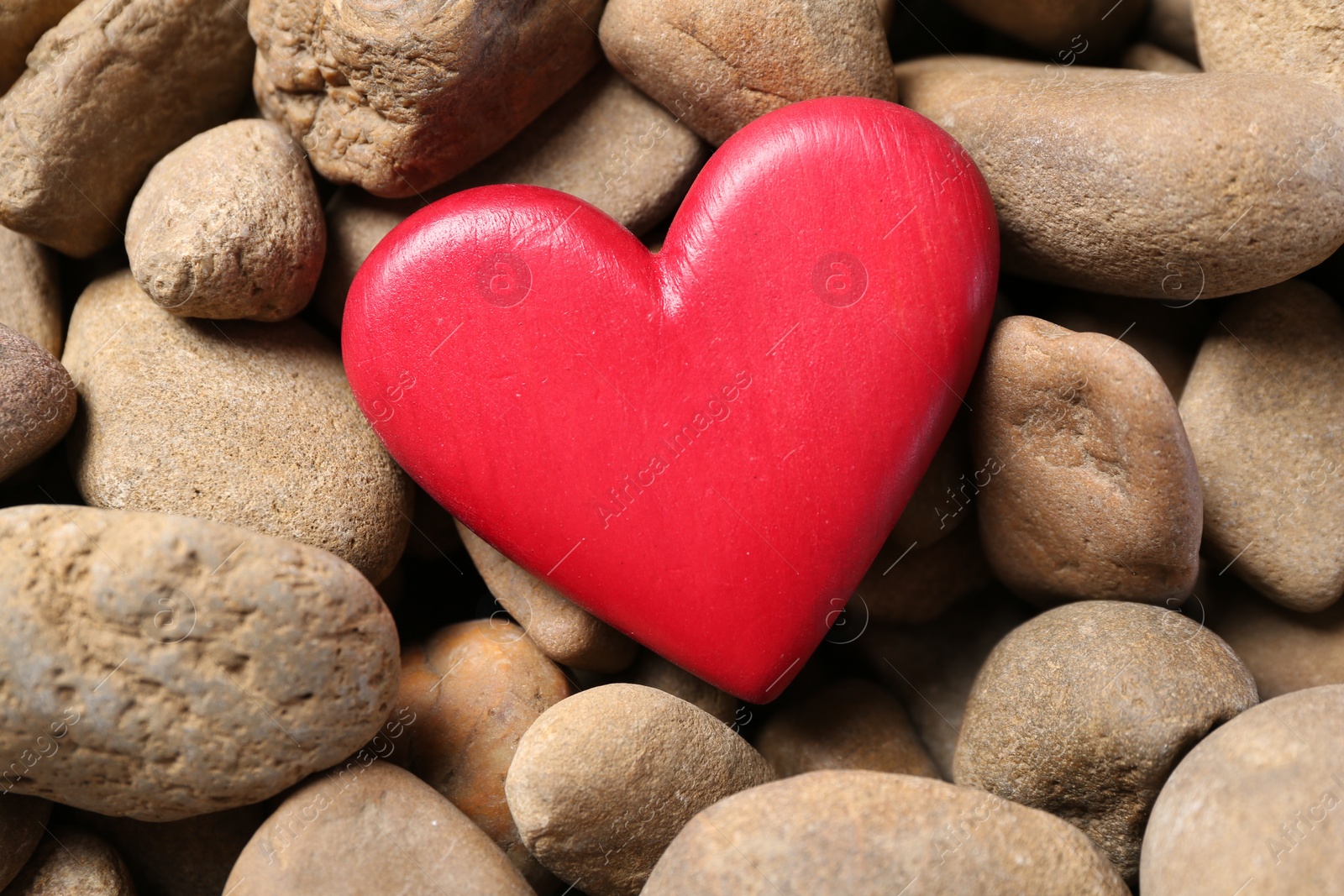 Photo of Red decorative heart on stones, top view