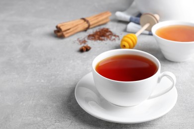 Photo of Freshly brewed rooibos tea on grey table. Space for text