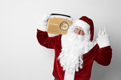 Photo of Santa Claus with vintage radio on light background. Christmas music