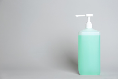 Photo of Dispenser bottle with antiseptic gel on light grey background. Space for text