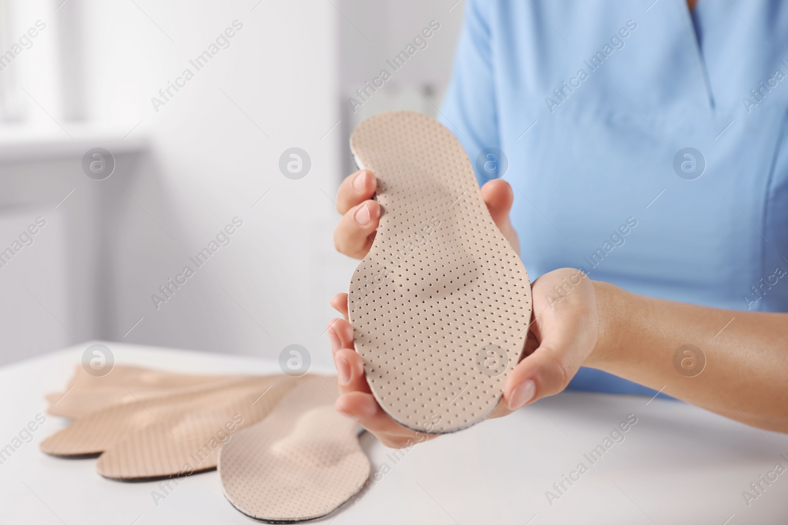 Photo of Female orthopedist showing insoles at table in hospital, closeup