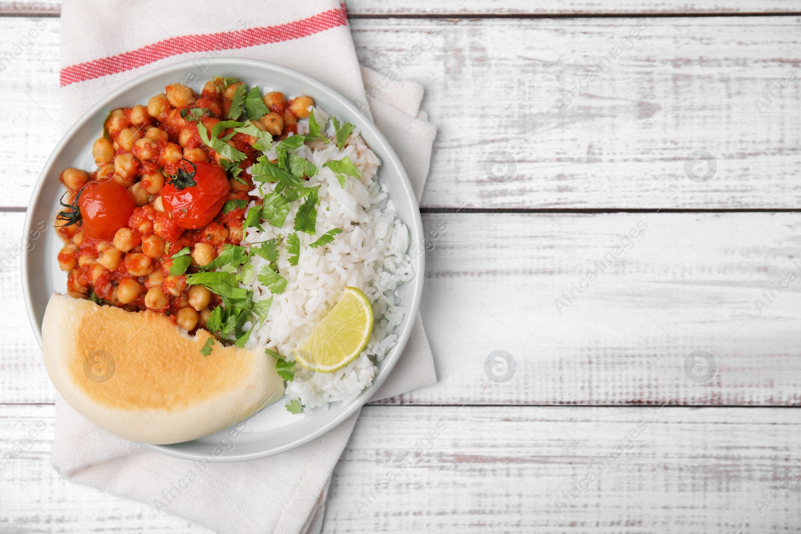 Photo of Delicious chickpea curry, rice and flatbread on white wooden table, top view. Space for text