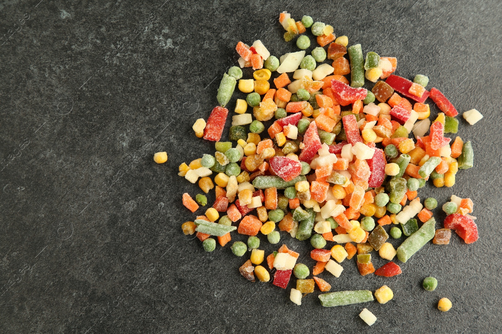 Photo of Mix of different frozen vegetables on gray table, top view. Space for text