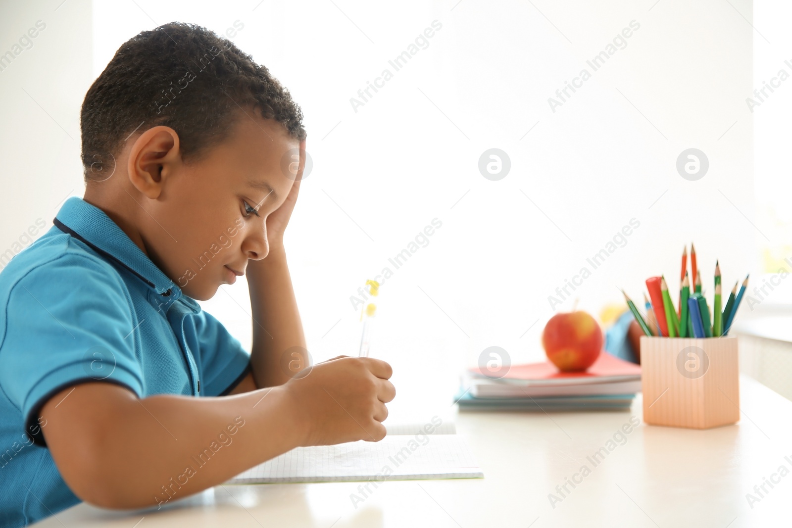 Photo of Cute little child doing assignment at desk in classroom. Elementary school