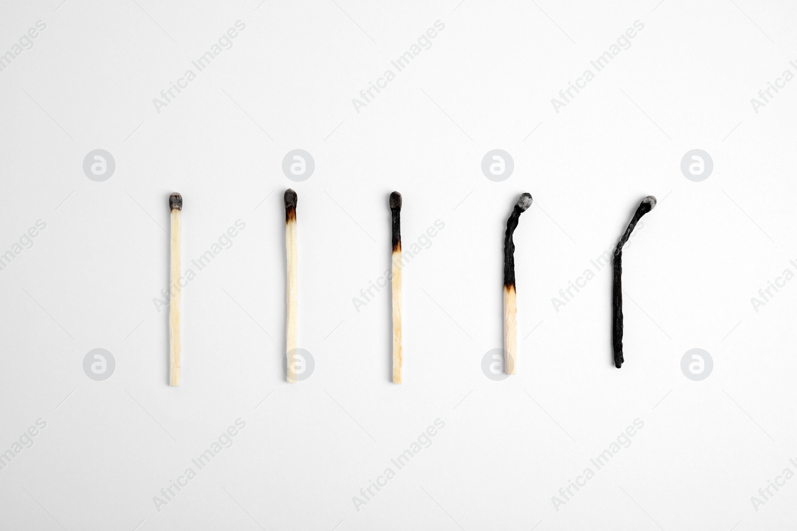 Photo of Different stages of burnt matches on white background, flat lay