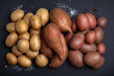 Photo of Different types of fresh potatoes on black table, flat lay.