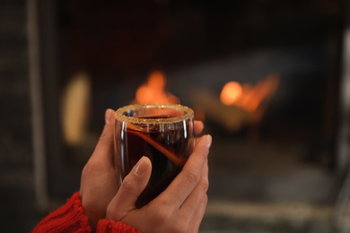 Photo of Woman with mulled wine near burning fireplace, closeup