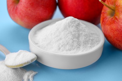 Photo of Sweet powdered fructose and fresh apples on light blue background, closeup