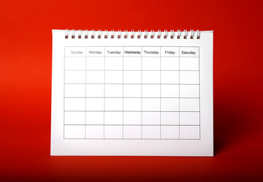 Photo of Blank paper calendar on red background. Planning concept