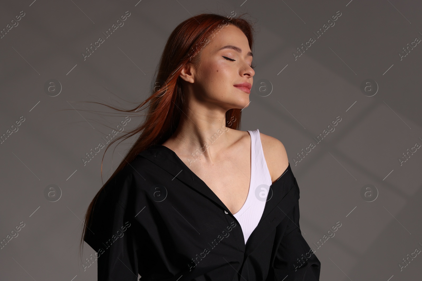 Photo of Beautiful young woman in black shirt on gray background