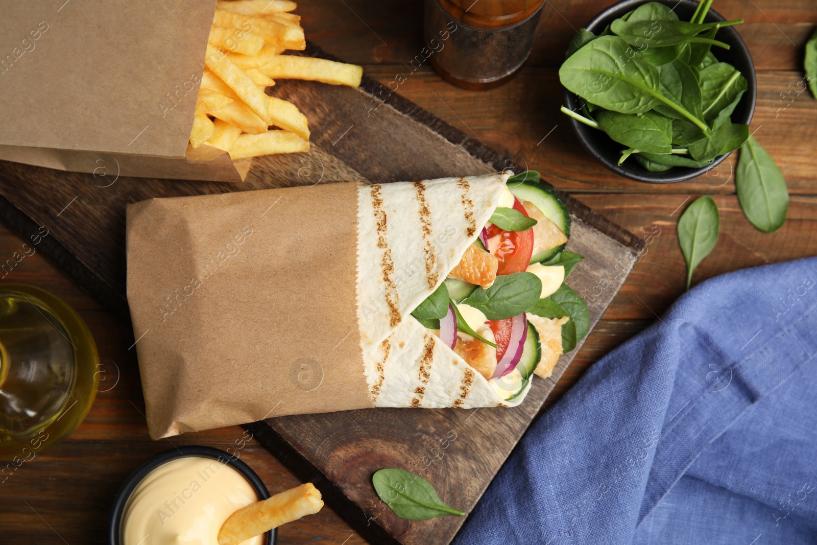 Photo of Delicious chicken shawarma and French fries served on wooden table, flat lay