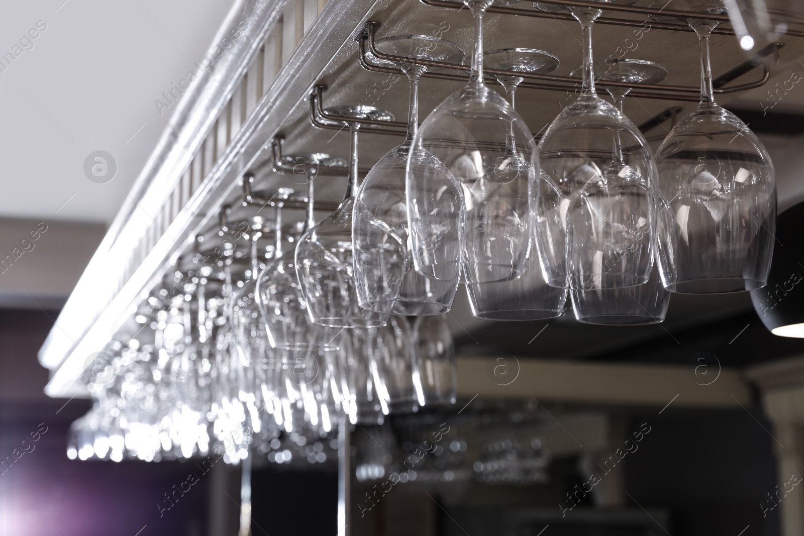 Photo of Set of empty clean glasses on bar racks