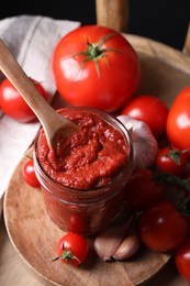 Taking tasty tomato paste with spoon from jar on wooden table, above view