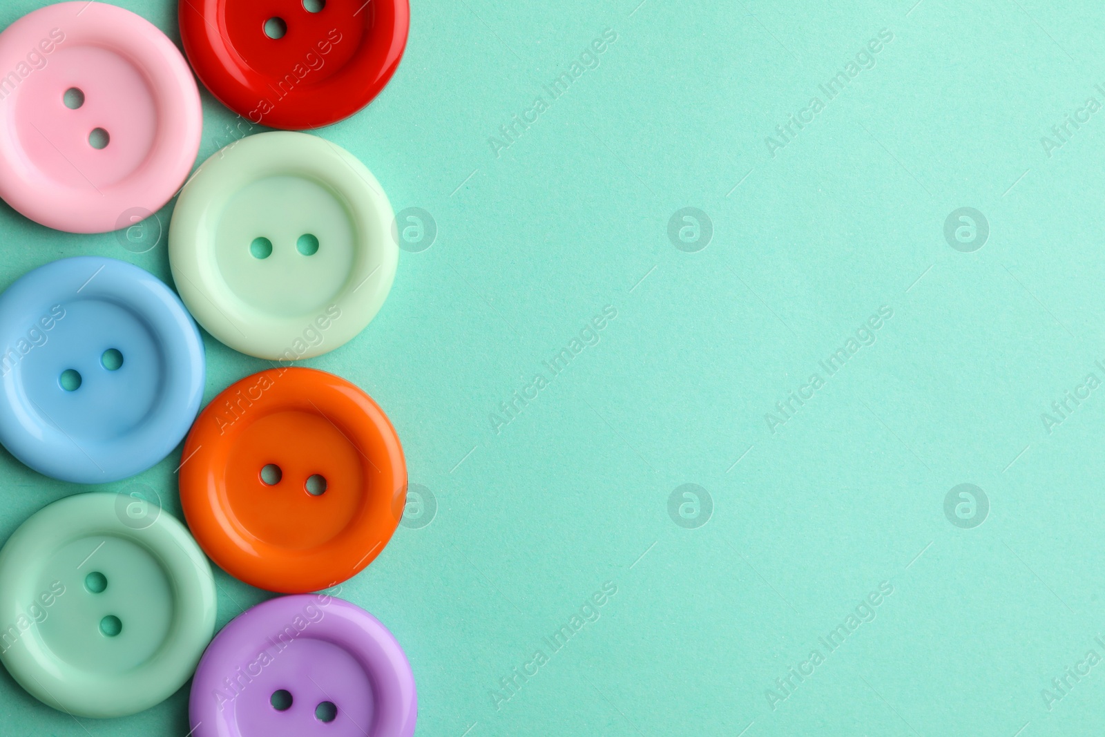 Photo of Many colorful sewing buttons on turquoise background, flat lay. Space for text