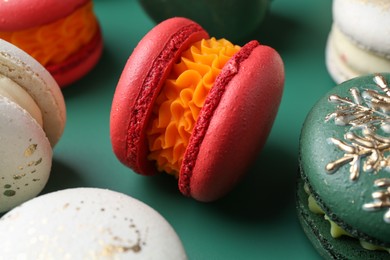 Photo of Beautifully decorated Christmas macarons on green background, closeup