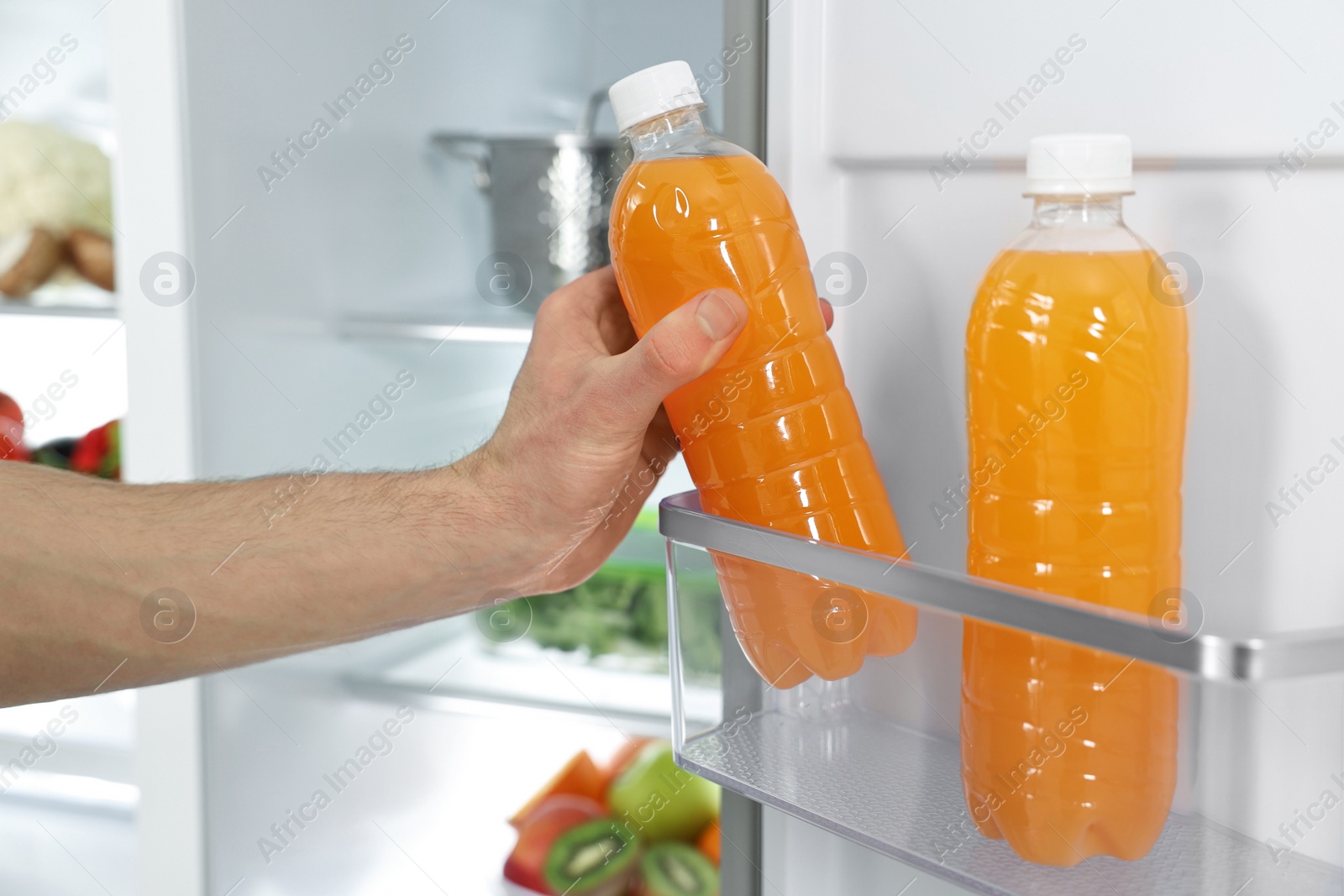 Photo of Man taking bottle of juice out of refrigerator, closeup