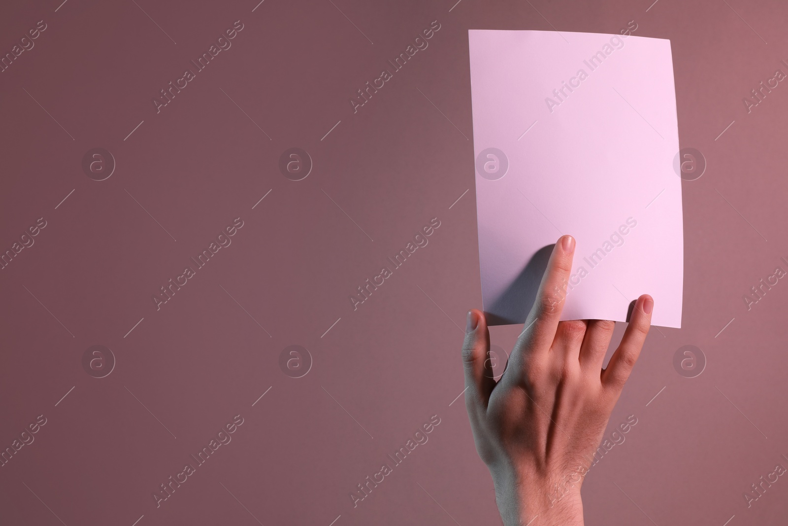 Photo of Man holding sheet of paper on color background, closeup. Mockup for design