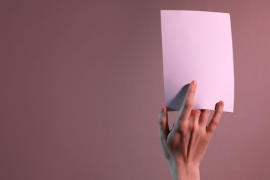 Photo of Man holding sheet of paper on color background, closeup. Mockup for design