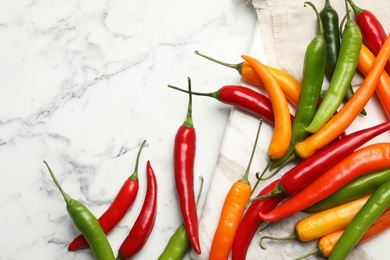 Photo of Different chili peppers on marble table, flat lay. Space for text