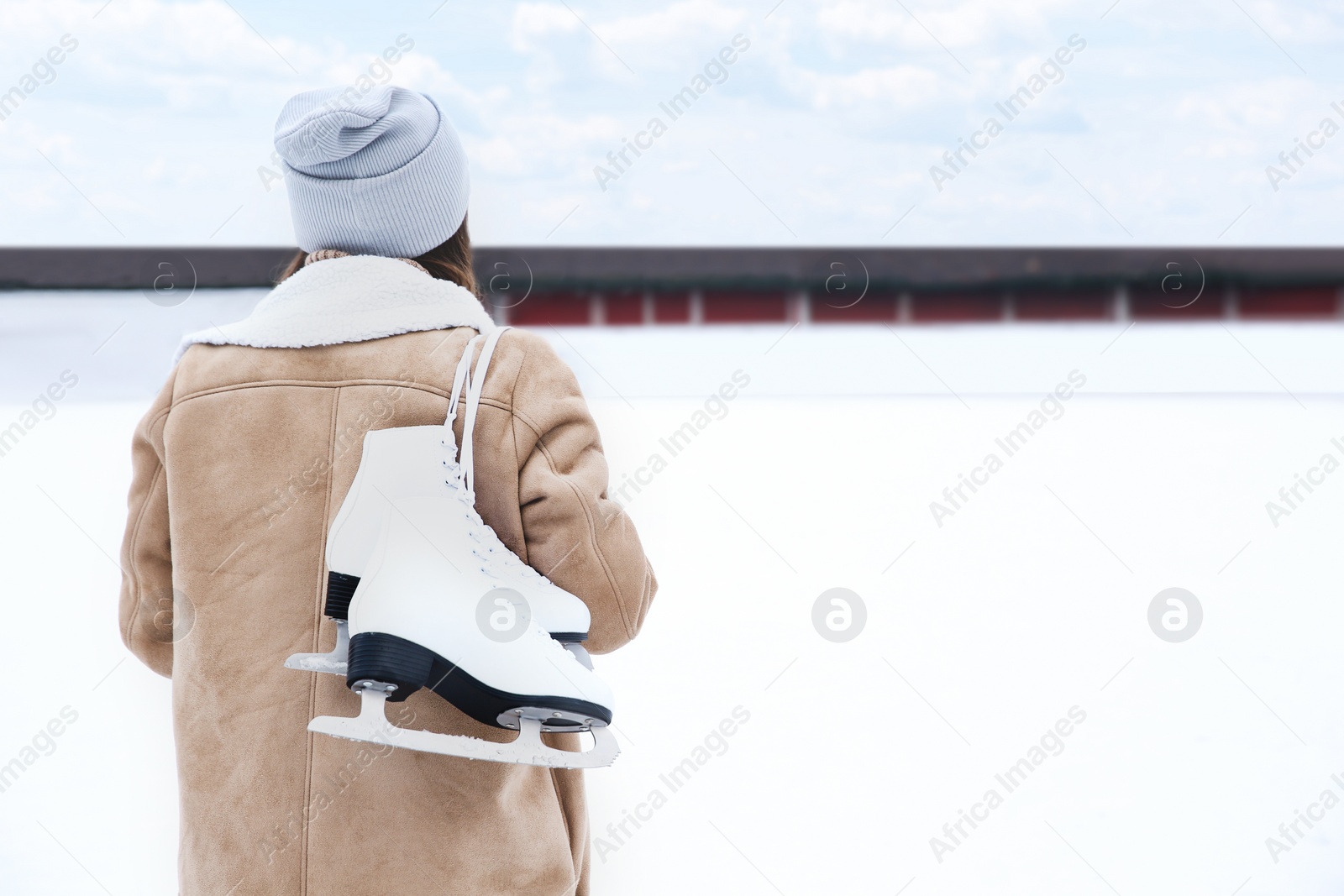 Image of Woman with figure skates near ice rink outdoors. Space for text