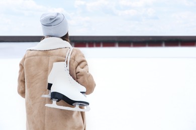 Image of Woman with figure skates near ice rink outdoors. Space for text