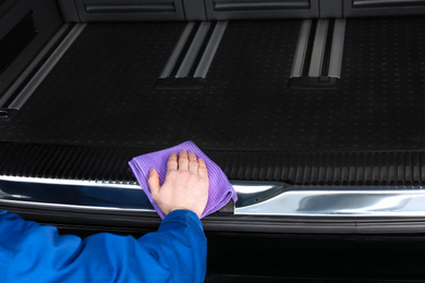 Worker wiping automobile trunk with rag at car wash, closeup