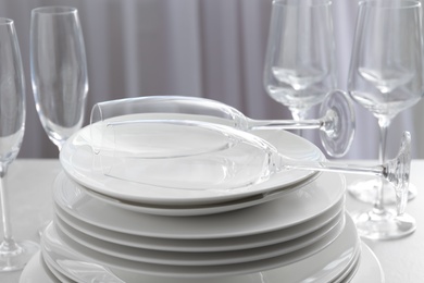 Photo of Stacked plates and glasses on table, closeup