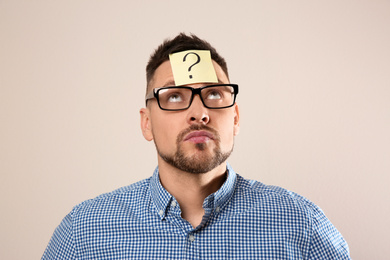 Photo of Man in eyeglasses with question mark on grey background