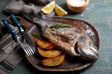 Delicious baked fish served on wooden rustic table, closeup. Seafood